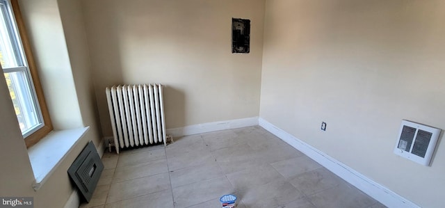 spare room featuring baseboards, visible vents, and radiator heating unit