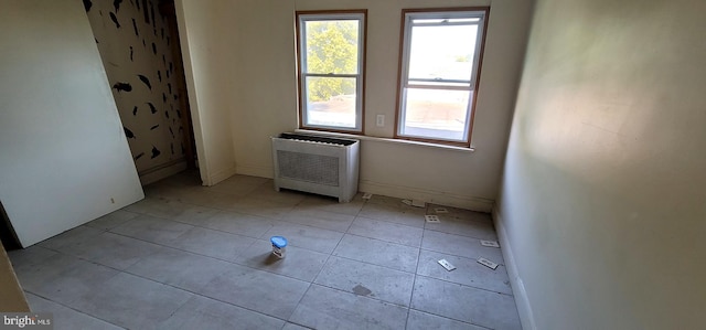 unfurnished room with radiator and light tile patterned floors