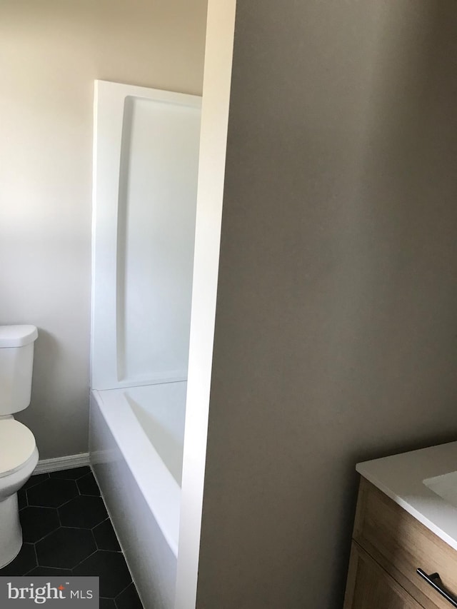 bathroom featuring tile patterned floors, a bath, vanity, and toilet