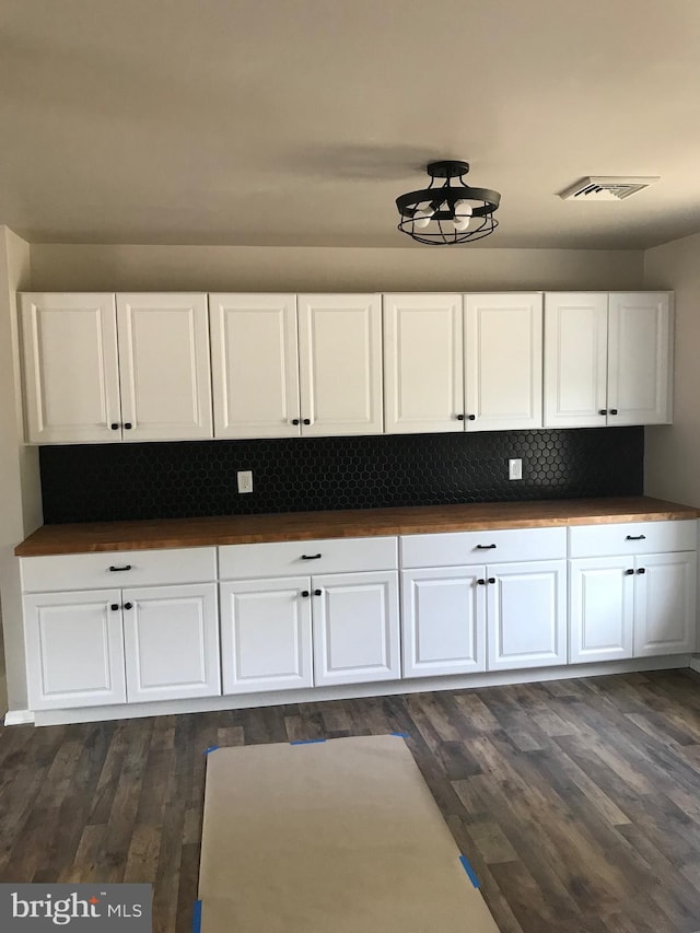 kitchen featuring white cabinets, dark wood-type flooring, and decorative backsplash