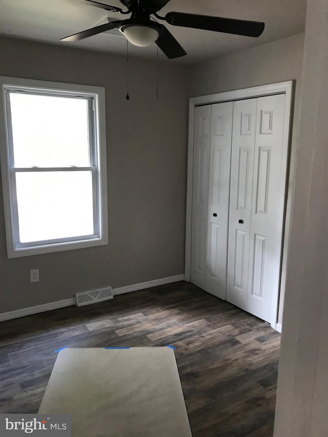 unfurnished bedroom with a closet, ceiling fan, and dark wood-type flooring