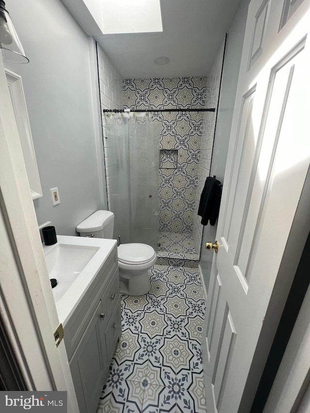 bathroom with vanity, toilet, a shower with shower curtain, and a skylight