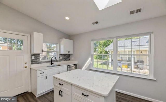 kitchen featuring white cabinetry, a kitchen island, a healthy amount of sunlight, and sink