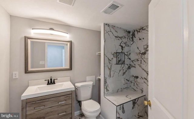 bathroom with vanity, toilet, and tiled shower