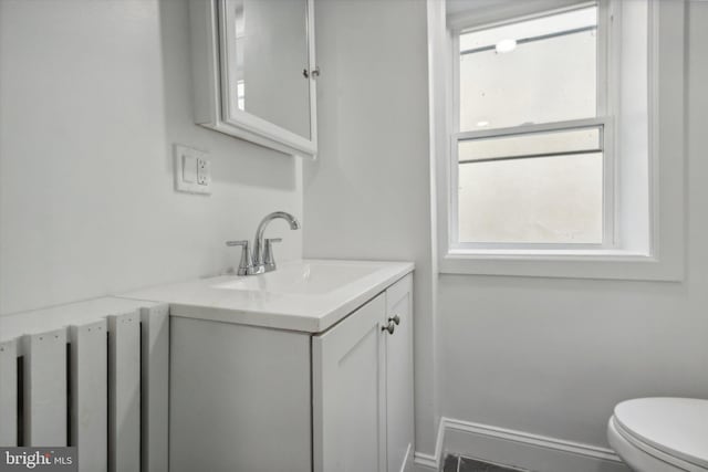 bathroom featuring vanity, a healthy amount of sunlight, and toilet