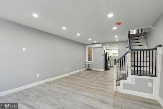 interior space featuring radiator, light hardwood / wood-style flooring, and a wall unit AC