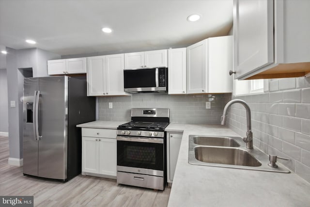 kitchen featuring sink, backsplash, white cabinetry, stainless steel appliances, and light wood-type flooring