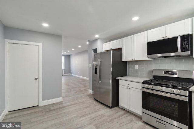 kitchen featuring backsplash, light hardwood / wood-style floors, white cabinetry, and stainless steel appliances