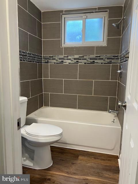 bathroom with hardwood / wood-style floors, tiled shower / bath combo, and toilet