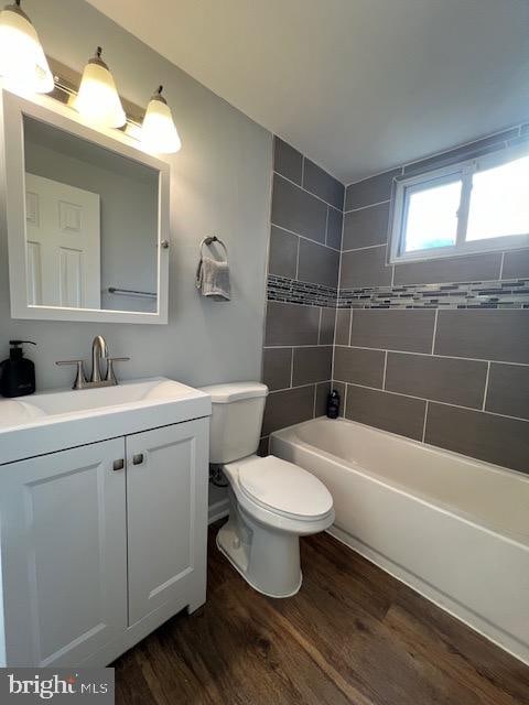 full bathroom with toilet, tiled shower / bath combo, vanity, and wood-type flooring