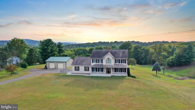 farmhouse featuring a lawn, covered porch, and an outbuilding