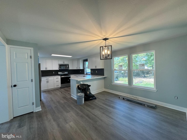 kitchen with appliances with stainless steel finishes, dark wood-type flooring, white cabinets, kitchen peninsula, and pendant lighting