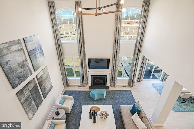 living room with light hardwood / wood-style flooring, a chandelier, and a high ceiling