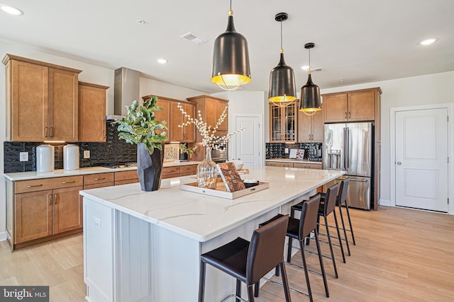 kitchen featuring appliances with stainless steel finishes, light wood-type flooring, decorative light fixtures, and a spacious island