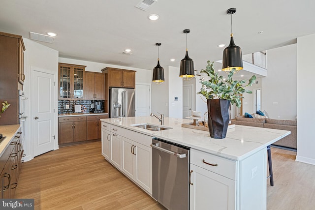 kitchen featuring a center island with sink, sink, light hardwood / wood-style floors, white cabinetry, and stainless steel appliances