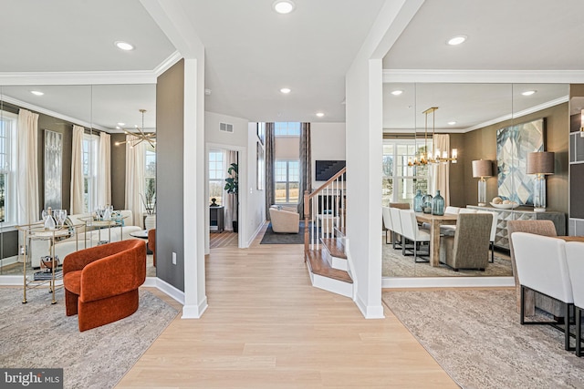 entrance foyer with a chandelier, crown molding, and light hardwood / wood-style floors