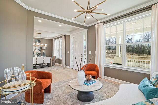 living room featuring a notable chandelier, crown molding, a wealth of natural light, and light hardwood / wood-style flooring