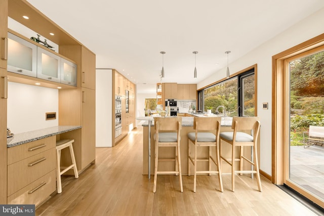 kitchen featuring light hardwood / wood-style flooring, kitchen peninsula, and light brown cabinets