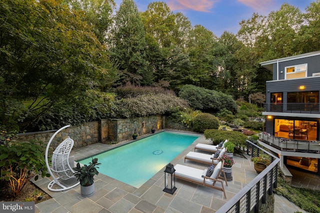 pool at dusk featuring a patio area