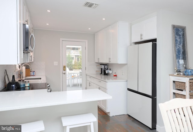 kitchen featuring white cabinets, kitchen peninsula, white fridge, backsplash, and dark hardwood / wood-style flooring