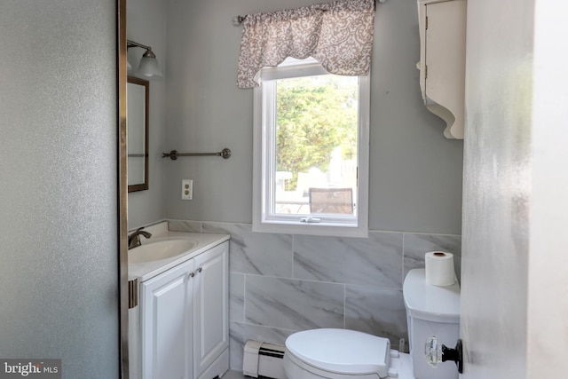 bathroom featuring vanity, baseboard heating, toilet, and tile walls