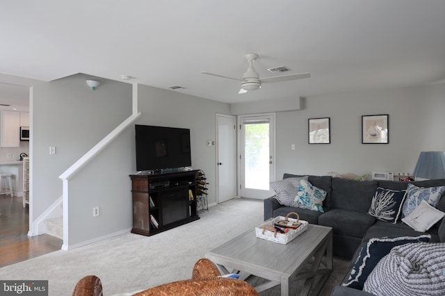 carpeted living room with ceiling fan