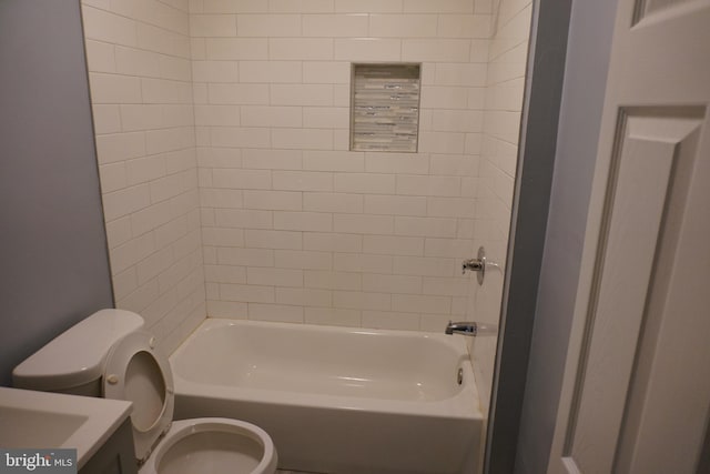 full bathroom featuring tiled shower / bath, vanity, and toilet