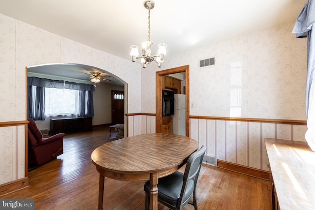 dining area with ceiling fan with notable chandelier and dark hardwood / wood-style flooring