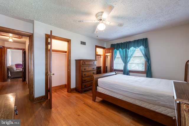 bedroom featuring light wood-type flooring, a textured ceiling, and ceiling fan