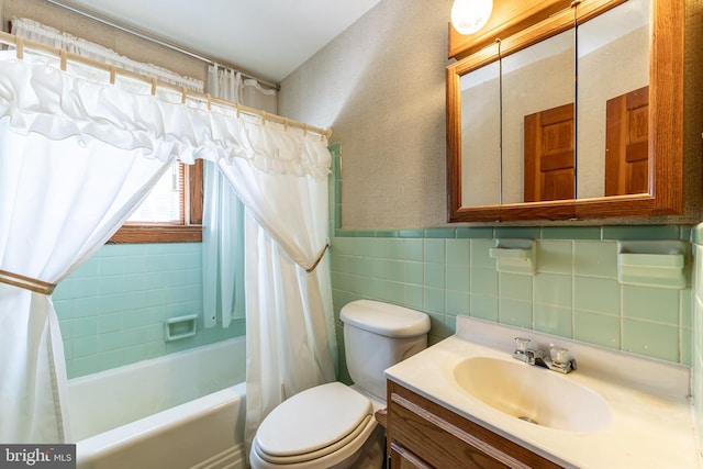 full bathroom featuring tile walls, shower / tub combo, vanity, and toilet