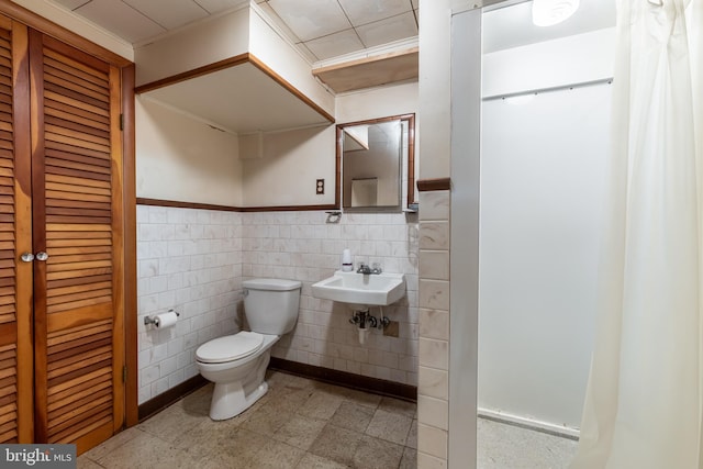 bathroom featuring tile walls, toilet, and sink