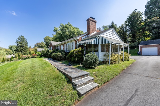 view of front of property with a garage, a front lawn, and an outbuilding