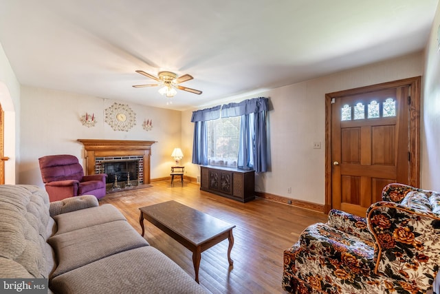 living room featuring a fireplace, light hardwood / wood-style flooring, ceiling fan, and a wealth of natural light