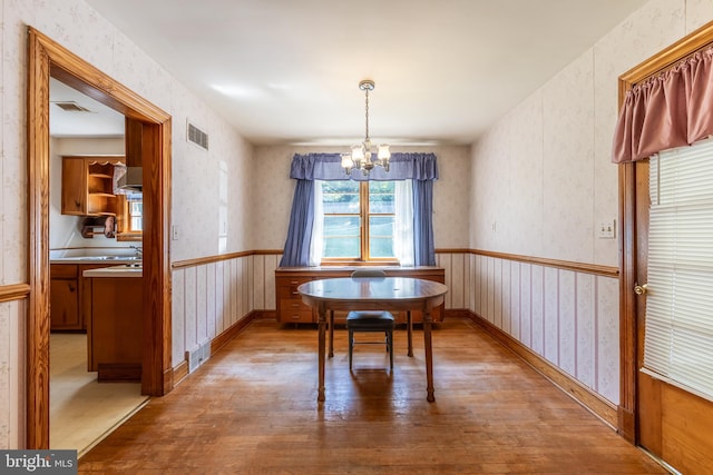 unfurnished dining area featuring wood-type flooring and a chandelier