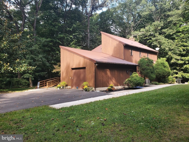 view of property exterior with an attached garage, fence, a yard, and metal roof