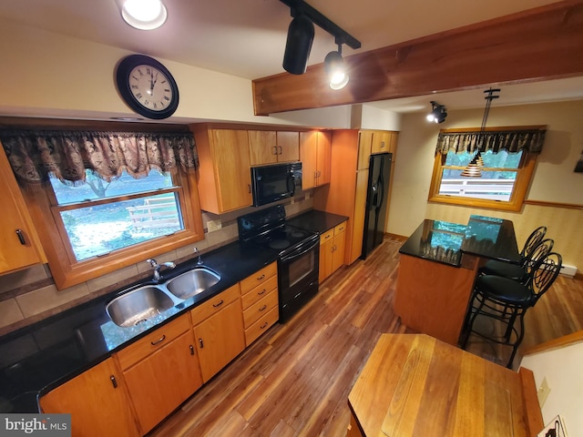 kitchen featuring hanging light fixtures, black appliances, sink, and dark hardwood / wood-style flooring