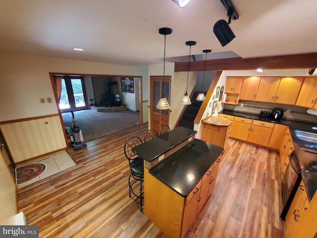 kitchen featuring dark countertops, light wood-style flooring, a kitchen island, and a sink