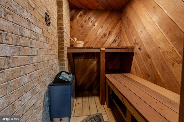 view of sauna / steam room with wood ceiling, brick wall, wooden walls, and hardwood / wood-style floors