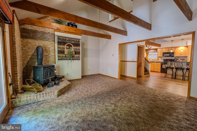 living room with beam ceiling, carpet floors, and a wood stove