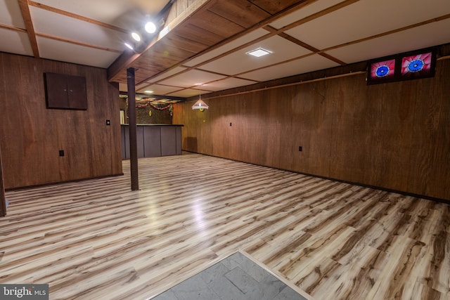 basement with light hardwood / wood-style flooring and wooden walls