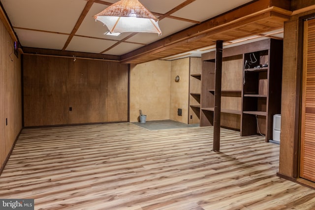 basement with light hardwood / wood-style floors and wood walls