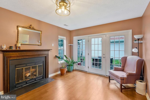 living area with a textured ceiling, hardwood / wood-style flooring, and a wealth of natural light