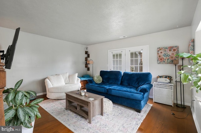 living room with a textured ceiling and dark wood-type flooring