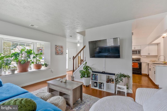 living room with light hardwood / wood-style flooring, a textured ceiling, and sink