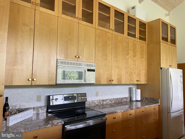 kitchen with dark stone counters, tasteful backsplash, and white appliances