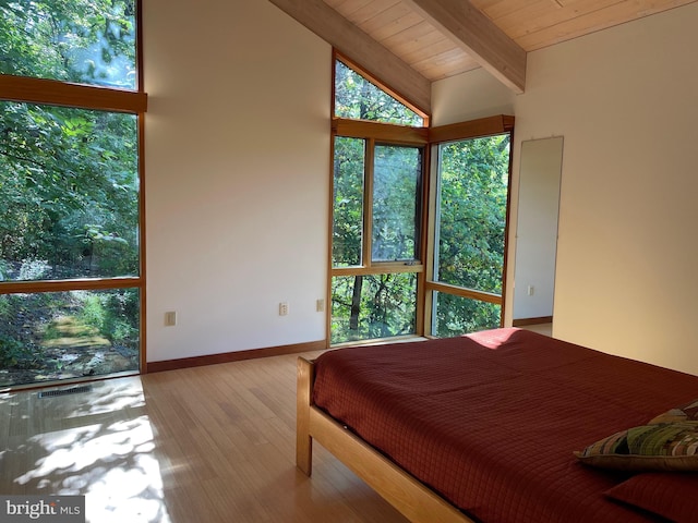 bedroom with multiple windows, vaulted ceiling with beams, light wood-type flooring, and wooden ceiling