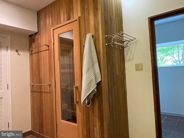 interior space with dark tile patterned floors and wood walls