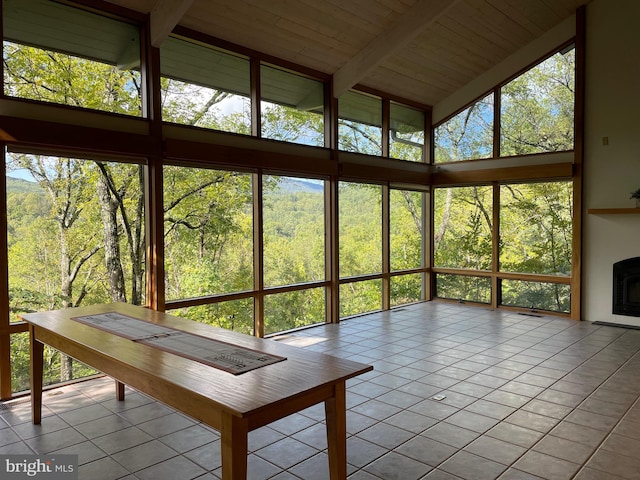 unfurnished sunroom with vaulted ceiling with beams, wooden ceiling, and a healthy amount of sunlight