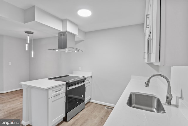 kitchen with sink, island range hood, stainless steel range with electric stovetop, light hardwood / wood-style flooring, and white cabinetry