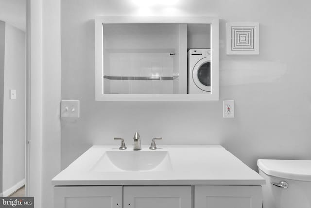 bathroom featuring washer / dryer, vanity, and toilet